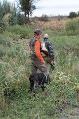 Mature hunter man holding a shotgun and walking through a field