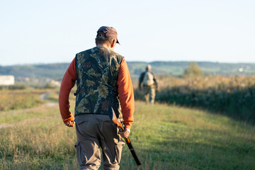 Fototapeta premium Mature hunter man holding a shotgun and walking through a field