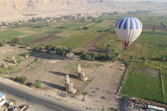 Aerial view of the Colossi of Memnon and hot air balloon in the morning, Luxor, Egypt