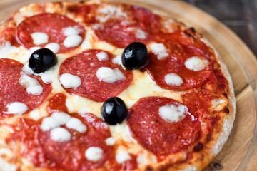 Pizza with salami and mozzarella cheese. Wooden background. Soft focus. Close up.	