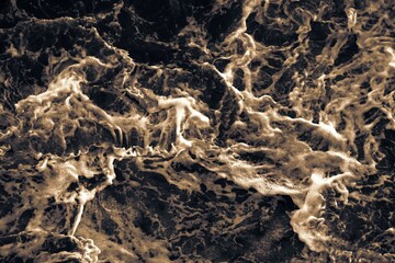 Top view. Foam on the ocean shore. Waves on the water. Contrasting image. Moody colors. Soft textured background