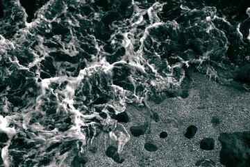 Top view. Foam on the ocean shore. Waves on the water. Contrasting image. Moody colors. Soft textured background