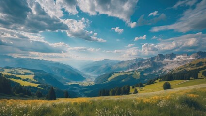 Obraz premium Stunning Panoramic Summer Landscape of the Alps under a Cloudy Blue Sky with Lush Green Fields and Majestic Mountains in the Background.