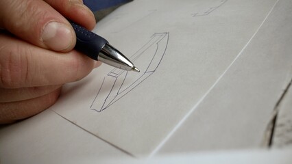 Hands drawing a simple wireframe of a website or app, adding details like buttons or icons, on a white sheet of paper