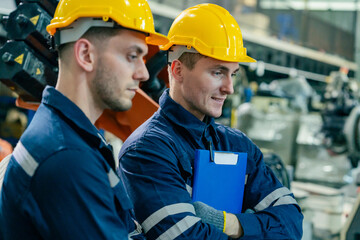Two workers in safety helmets discuss their project in a manufacturing facility during the...