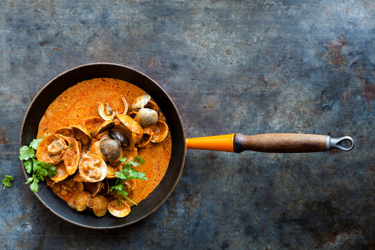 Skillet of seafood  in creamy curry sauce. Food shellfish presentation on grey surface