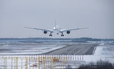 The plane is landing to runway in winter