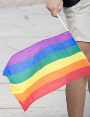 unrecognizable person holding rainbown flag pride day. summer. stret. Horizontal