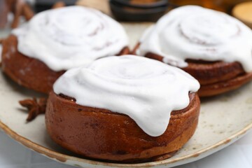 Tasty cinnamon rolls with cream and spices on white table, closeup