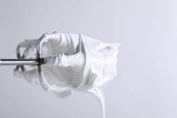 Whisks with whipped cream on white background, closeup. Space for text