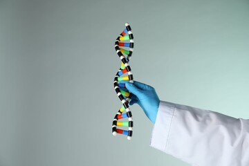 Scientist with DNA structure model on color background, closeup