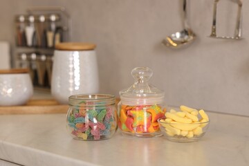 Tasty gummy candies on white table in kitchen