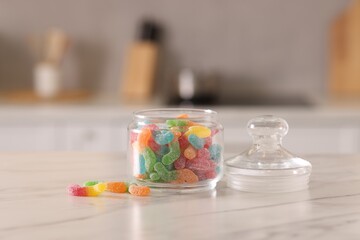 Gummy candies in glass jar on white marble table indoors