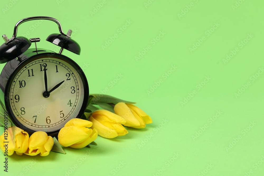 Poster spring time. alarm clock and beautiful tulips on green background, space for text