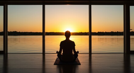 Person meditating in a peaceful room with a river view at sunset