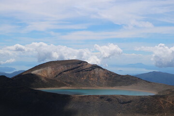 Breathtaking view of an alpine lake nestled within a volcanic landscape in New Zealand. The turquoise waters contrast with the rugged terrain, creating a striking scene perfect for adventure and explo