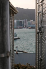 Unique framed view of a New Zealand waterfront city through a narrow alleyway. A blend of urban architecture and harbor scenery, perfect for themes of exploration, travel, and hidden perspectives.