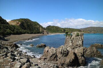 Rugged New Zealand coastline with rocky cliffs, turquoise waters, and lush green hills. A perfect travel and adventure image capturing untouched nature, scenic landscapes, and coastal beauty.