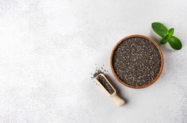 Wooden bowl of dried chia seeds on gray background. Top view, copy space. Chia seeds - rich...