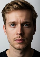 Obraz premium Portrait of a Serious Young Man with Blond Hair and Blue Eyes, Looking Intently