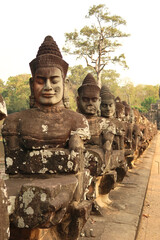 Many stone giants are lined up next to the road to the Southern Gate, holding on to the body of a...