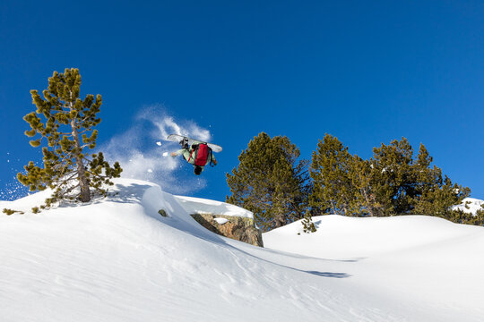 Snowboarder flips through clear sky in snowy landscape