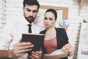 Private detective agency. Man and woman are looking at clues on tablet in office.