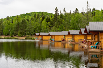 Naklejka premium Wooden small cottages for camping on the shore of a forest lake, Quebec, Canada