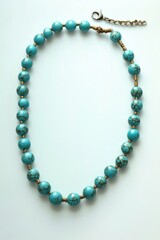 Obraz premium A close-up of a turquoise bead necklace lying on a white surface, ready to be worn or used as jewelry