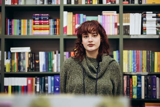 Young woman posing in front of colorful bookshelves