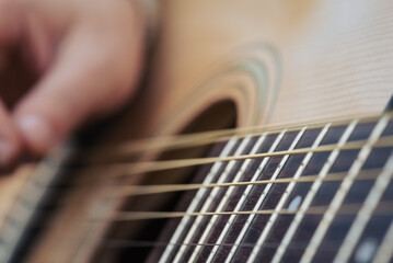 Close up of strings of a guitar while playing. Hand of a woman playing the guitar, strings vibrate...