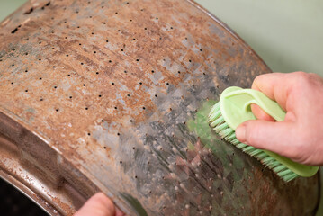 Cleaning washing machine drum. Hands of a man with a brush cleaning washing machine drum from dirt,...