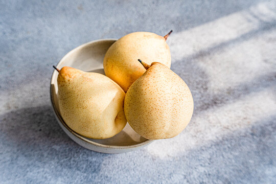 Fresh Chinese white pears in a bowl on a textured surface