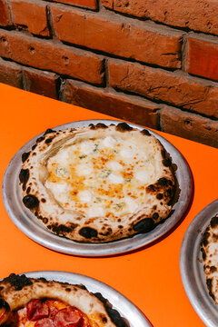 Delicious Four Cheese Pizza on a Vibrant Orange Table