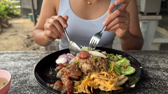 Cropped Portrait of Woman Eating Fried Rice Mixed With Shrimp Paste (Khao Khluk Kapi) In Thai Restaurant. closeup shot