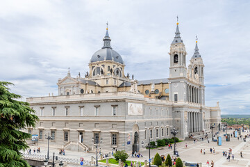 Obraz premium Madrid, Spain - october 02, 2024: Facade of the Almudena Cathedral of Madrid with tourists walking around in Madrid, Spain