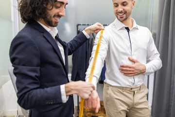 Tailor measuring client for custom suit fitting in a suit store