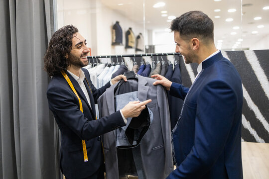 Tailor Assisting Client with Suit Selection in Fashion Store