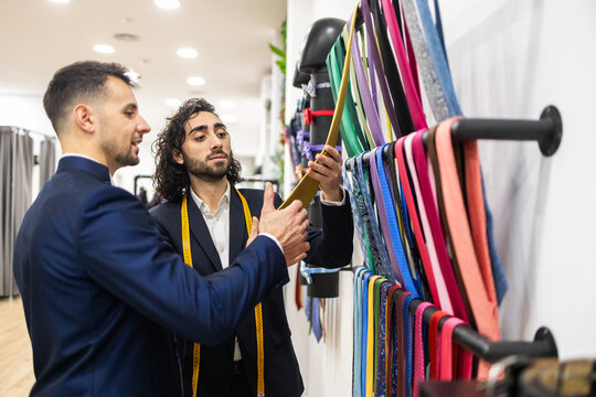 Tailor assisting customer choosing ties in a suit store