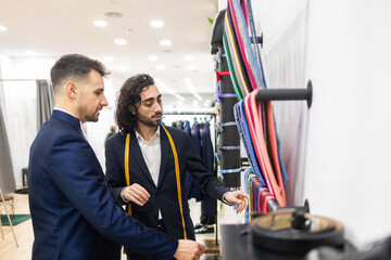 Tailor assisting client with suit selection in a suit store
