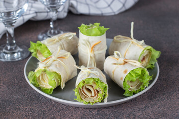 Appetizer from pita bread with ham, cheese and lettuce on gray plate