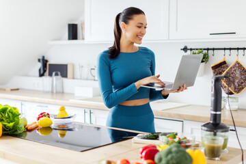 Happy fit lady in sportswear using laptop browsing nutritious recipes for slimming, planning menu...
