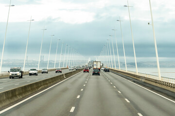 Lisbon, Portugal - October 31, 2024: Traffic on The Vasco da Gama Bridge (Portuguese: Ponte Vasco da Gama) is a cable-stayed bridge in a rainy day.