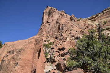 Fototapeta premium Rugged cliff with sparse vegetation against a clear blue sky. Colorado National Monument, USA