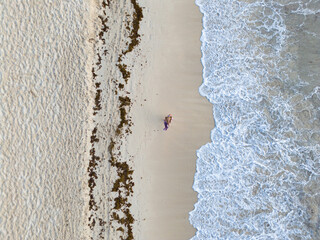 The woman watching Caribbean Sea from the sandy beach in Mexico at sunrise, aerial view
