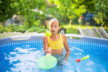 Young girl playing with a racket in a swimming pool