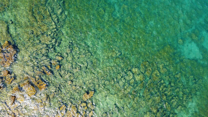 Mediterranean, Tropical Crystal Clear Water, Rocky Seabed and Underwater Stones. Golden underwater stones and natural patterns on the scene. Top down aerial perspective shows coastal geology.