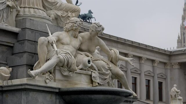 Close-up of the Pallas Athena Fountain in front of the Austrian Parliament in Vienna. The marble statues depict Greek deities with water flowing from a jug.