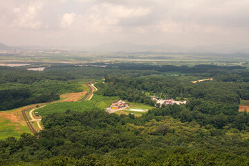 Aerial View Of Lush North Korea Green Forests, Winding Roads, And Military Outposts In Restricted Border Zone