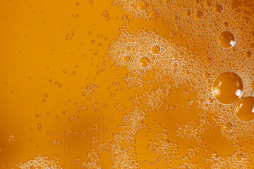 Abstract orange liquid background with bubbles on surface vegetable oil top view.